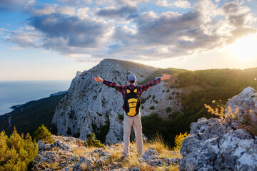 Adventurous man is on top of the mountain and enjoying the beautiful view during a vibrant sunset