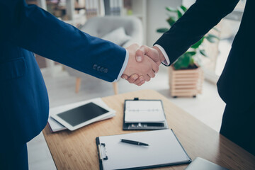 Cropped close-up view of two male hands shaking over table desk signed corporate contact assignment...