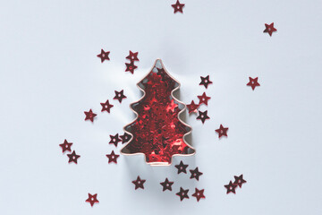 Christmas tree shape cookie cutter with red star confetti on blue background