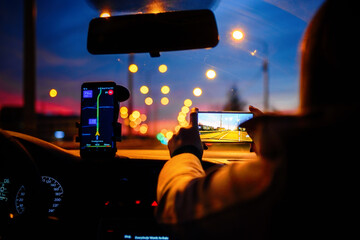 Smartphone with map on the screen in car. Automobile dashboard in night mode.