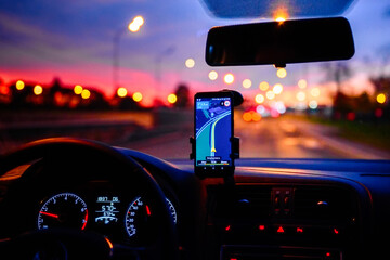 Smartphone with map on the screen in car. Automobile dashboard in night mode.