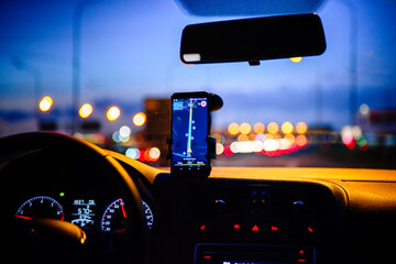 Smartphone with map on the screen in car. Automobile dashboard in night mode.