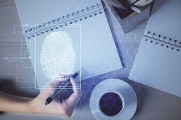 Blue fingerprint hologram over woman's hands taking notes background. Concept of protection. Double exposure