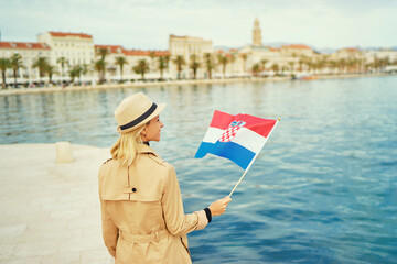 Enjoying vacation in Croatia. Young traveling woman with national croatian flag walking on Split...