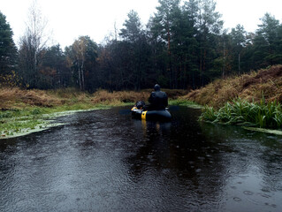 River rafting in the fall. A young man rafts in a boat on a river in the wild. Packrafting in...