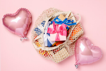 Shopping Bag with gift and heart shaped air balloon on a pink background. Gifts concept for family, loved ones, christmas, valentines day. Banner. Flat lay, top view