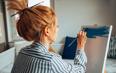 Beautiful artist woman painting in her room.
