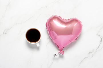 Cup with coffee and air balloon heart on a marble table. Concept of dinner, Valentine's Day, date, meeting, love of coffee. Flat lay, top view