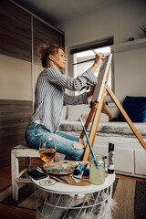 Beautiful artist woman painting in her room.