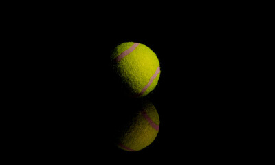 Bright Yellow Tennis Ball on dark mirror with reflections