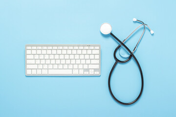 Keyboard and medical stethoscope on a blue background. Concept medicine, hospital, safety, epidemic, doctor's call, online, consultation. Banner. Flat lay, top view