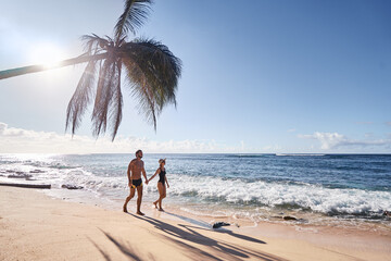 Honey moon on the sea shore. Back view of loving couple walking together on beautiful tropical white sand beach.
