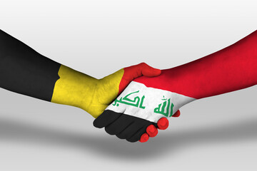 Handshake between iraq and belgium flags painted on hands, illustration with clipping path.