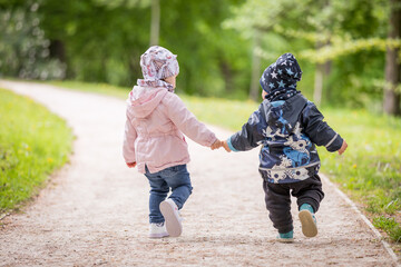 Little boy and girl (2 years old) walking together hand in hand being biggest friends