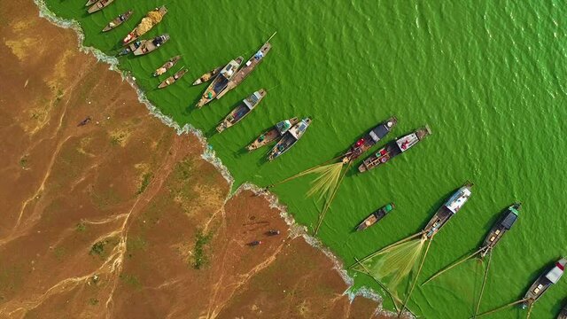 Aerial view of Ben Nom fishing village, a brilliant, fresh, green image of the green algae season on Tri An lake, with many traditional fishing boats anchored. Location in Dong Nai province, Vietnam