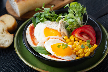 Healthy food Super Breakfast concept  fried eggs and micro-green salad with corn and tomato in Skillet iron pan with copy space