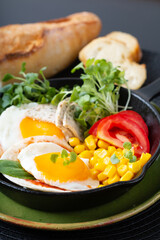 Healthy food Super Breakfast concept  fried eggs and micro-green salad with corn and tomato in Skillet iron pan with copy space