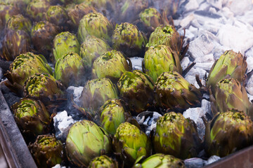Fototapeta na wymiar Closeup of artichokes being grilled on burning charcoal in brazier..