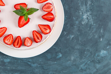 Sweet breakfast, delicious cheesecake with fresh strawberries and mint, homemade recipe without baking, on a dark blue stone table. Copy space.