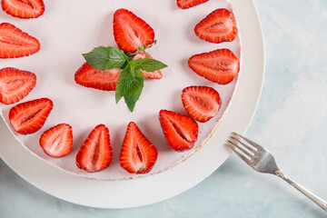 Sweet breakfast, delicious cheesecake with fresh strawberries and mint, homemade recipe without baking, on a blue stone table. Copy space.