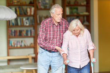 Senior stützt seine behinderte Ehefrau mit Krücken