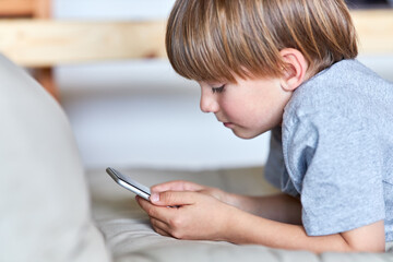 Obraz na płótnie Canvas Kleiner Junge schaut auf sein Smartphone