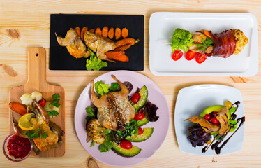 Close up of delicious fried partridge and quail with avocado, greens and tomatoes