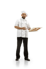 Cooker, chef, baker in uniform isolated on white studio background with croissants. Young man, restaurant cooker's portrait. Business, foor, professional occupation, emotions concept. Copyspace for ad