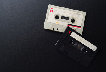 Two old white and black vintage audio cassettes on a black background, top view.
