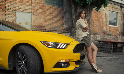 Fototapeta na wymiar Young woman stands near yellow sport car.