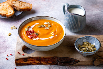 Vegetarian autumn pumpkin and carrot soup with cream, seeds and spices. Fall and winter comfort, healthy slow food