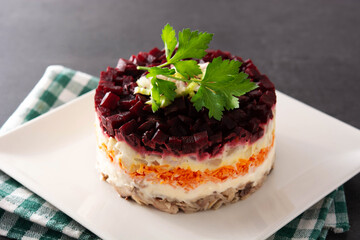 Traditional Russian herring salad with beetroot and carrots on black background	