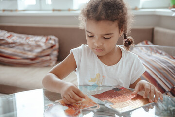 Cute little girl playing with colorful constructor at home.