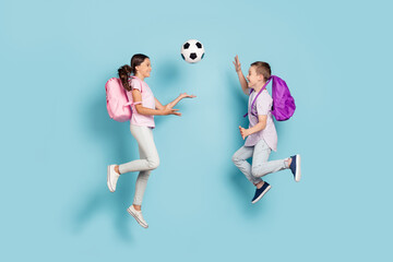 Fototapeta na wymiar Full length body size view of two attractive small little cheerful friends friendship jumping play soccer cup goal throwing ball hobby leisure isolated blue pastel color background