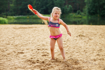 Girl throws sand. Beautiful girl playing with sand on beach. child having fun. vacation happiness and freedom concept.
