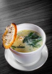 chicken cream soup in white bowl on black wooden table background