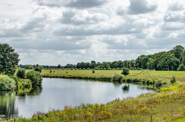 Fototapeta na wymiar Bend in the river Vecht near Zwolle, The Netherlands in a green landscape under a dramatic sky on a summer day