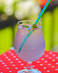 Lavander lemonade drink in a glass with plastic straw outside. Fresh natural organic herbal soft drink.