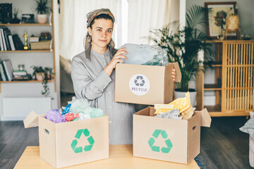 Woman sorting different waste. Sorting waste (paper, glass, plastic) into cardboard box with...