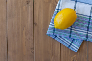 Fresh ripe juicy whole lemon on a wooden table on a towel.