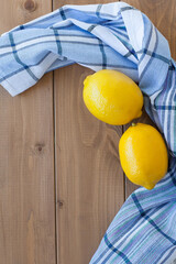 two ripe yellow lemons on the table near the kitchen towel