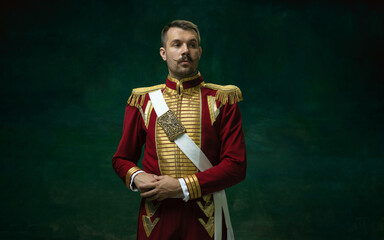 Highly serious. Young man in suit as Nicholas II isolated on dark green background. Retro style,...