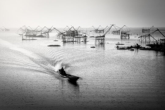 Black and white image of traditional square fishnet equipment at sunrise in Pakpra Canal, Phatthalung, Thailand