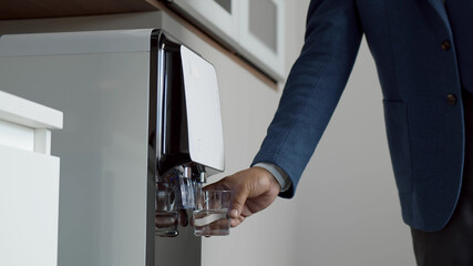 Close up of businessman hand pouring water from cooler in kitchen