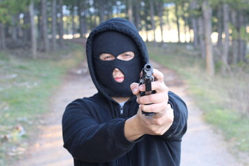 Bandit holding a gun in the forest