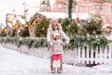 Naklejka premium Cheerful family, mother and little girl having fun on Christmas market.