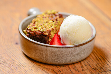 Brownie dessert with ice cream and fresh organic strawberry. Served in a traditional bowl. Georgian cuisine concept.