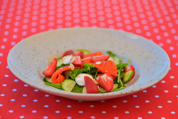 Strawberry and salmon salad with cream cheese served in a plate. Healthy meal. Eating out in restaurant. Summer terrace.