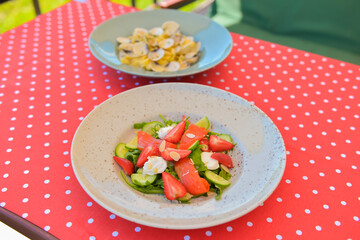 Served table at summer terrace cafe. Salmon salad and pasta with clams. Eating out in restaurant, summer terrace.
