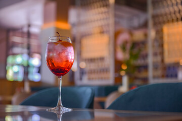 A glass with the red citrus cocktail. Alcohol summer beverage in a wine glass. Refreshing drink with ice.